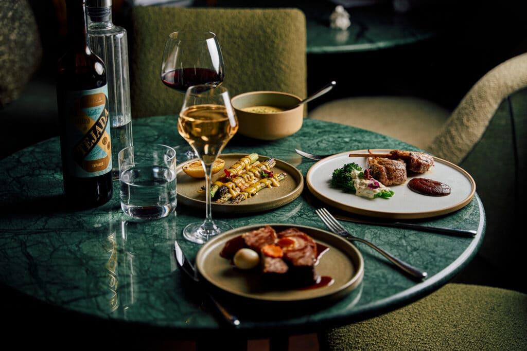 lamb shanks and meat with a glass of red and white wine at lilli by akira back
